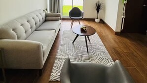 A modern living room with a sectional sofa, a round coffee table, and a single armchair. There is a sliding glass door leading to a balcony. - Bohemian Zen House Entire home in Mazatlán, Mexico (Mazatlán)