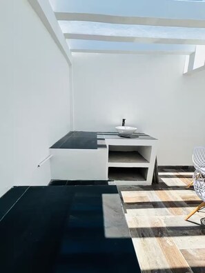 Eine moderne Küche mit weißer Arbeitsplatte, schwarzer Spritzschutzwand und einem weißen Spülbecken.