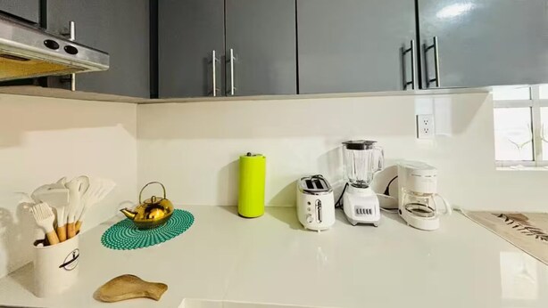 A kitchen with grey cabinets, a white countertop, and various appliances including a toaster, blender, and coffee maker. - Bohemian Zen House Entire home in Mazatlán, Mexico (Mazatlán)