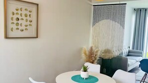 A dining area with a round table, white chairs, a potted plant, and a hanging light fixture. - Bohemian Zen House Entire home in Mazatlán, Mexico (Mazatlán)