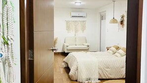 A bedroom with a bed, a sofa, a wall-mounted air conditioner, and a macrame wall hanging. - Bohemian Zen House Entire home in Mazatlán, Mexico (Mazatlán)