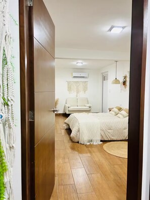 Ein Schlafzimmer mit einem Bett, einer Couch, einer Wand-Klimaanlage und einem Wandbehang aus Makramee.