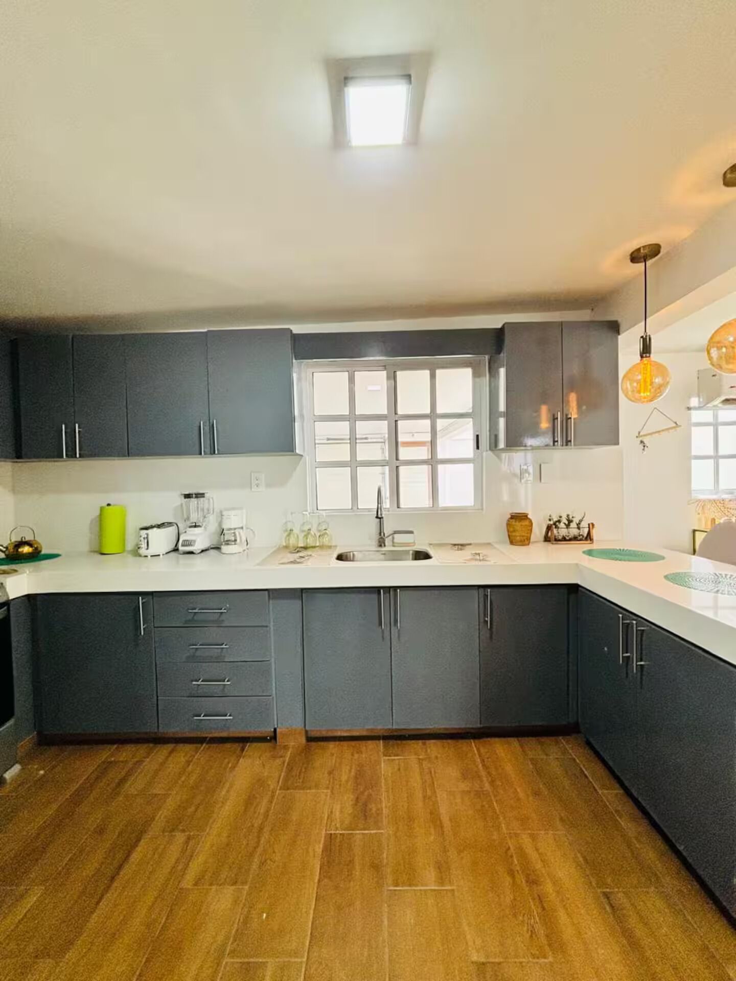 Una cucina moderna con mobili scuri, una finestra e un pavimento in legno.