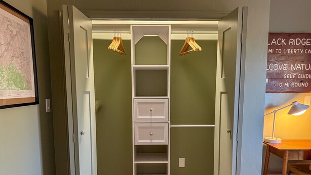 Ein begehbarer Kleiderschrank mit eingebauter Leiter, Regalen und einer Kleiderstange.