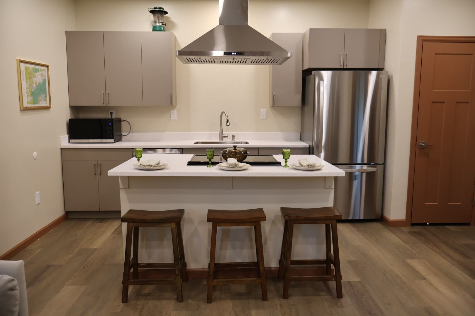 Une cuisine dotée d’un îlot central, d’appareils électroménagers en acier inoxydable et de tabourets en bois.