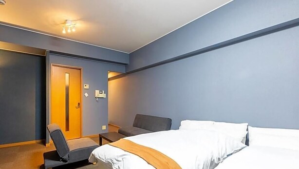 Una habitación de hotel con dos camas, un escritorio, una silla y una puerta.