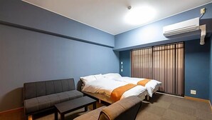 Una habitación con cama, sofá, una mesita y aire acondicionado.