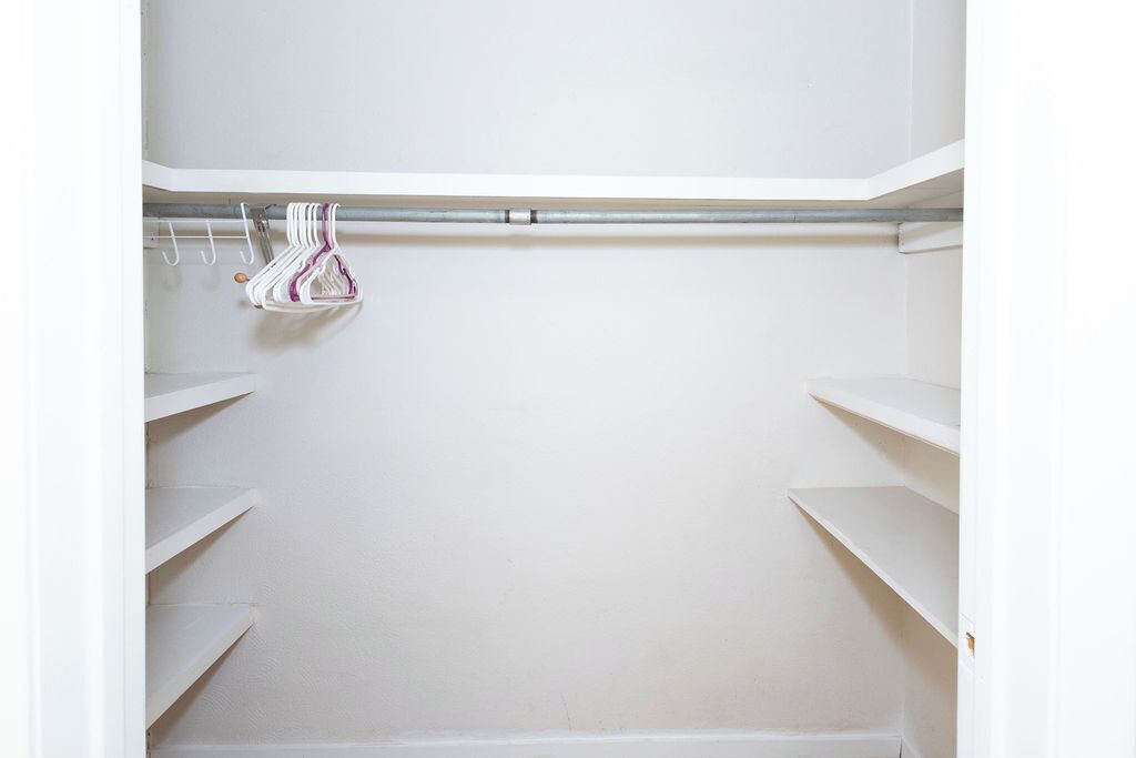 Un placard blanc avec des étagères et une tringle pour suspendre les vêtements.