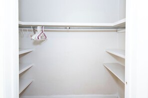 Un placard blanc avec des étagères et une tringle pour suspendre les vêtements.