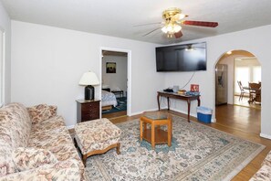 A living room with a sofa, a coffee table, a television, and a ceiling fan.