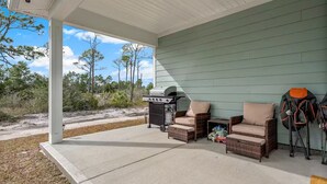 A covered patio with wicker furniture, a grill, and outdoor gear. - Golf Cart • EV Charger • Pool • Walk to Beach • 2 Kitchens • Private Suite (Port St. Joe)