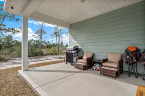 A covered patio with wicker furniture, a grill, and outdoor gear. - Golf Cart • EV Charger • Pool • Walk to Beach • 2 Kitchens • Private Suite (Port St. Joe)