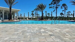 A swimming pool area with a paved deck, lounge chairs, and palm trees. - Golf Cart • EV Charger • Pool • Walk to Beach • 2 Kitchens • Private Suite (Port St. Joe)