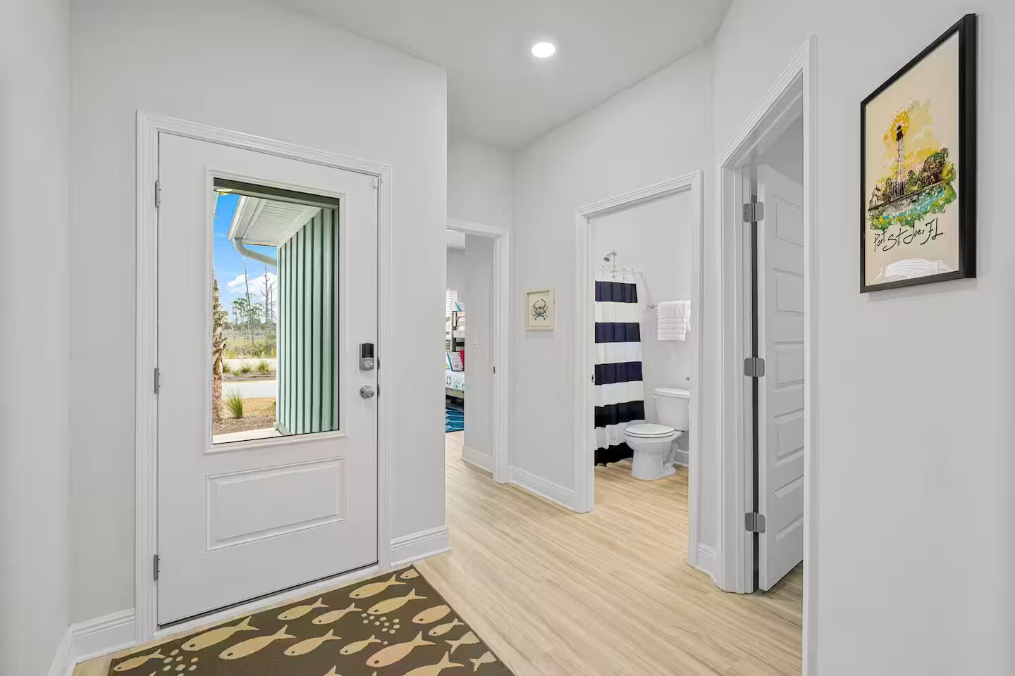A hallway with a door leading to a bathroom with a striped shower curtain.