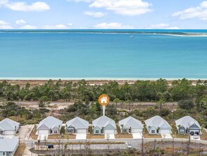 A coastal residential area with houses, a clear view of the ocean, and a prominent house icon. - Golf Cart • EV Charger • Pool • Walk to Beach • 2 Kitchens • Private Suite (Port St. Joe)