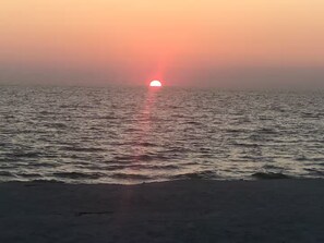 Ein Sonnenuntergang über einem ruhigen Gewässer, dessen Oberfläche die Farben des Himmels spiegelt.