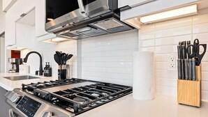 A modern kitchen with a stainless steel stove, a coffee machine, and a knife block. - Modern DTLA Apartment Minutes from Dodger Stadium (Los Angeles)