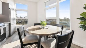 A modern kitchen with a dining area, large windows, and a view of the city. - Modern DTLA Apartment Minutes from Dodger Stadium (Los Angeles)