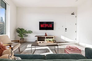 A modern living room with a flat-screen TV mounted on the wall, a coffee table, a sofa, and a door.