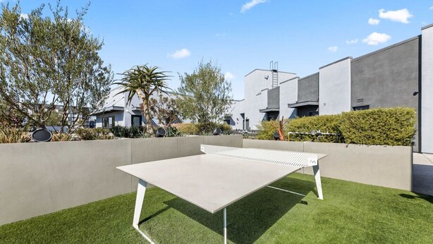 A ping pong table on artificial grass with a modern building in the background. - Modern DTLA Apartment Minutes from Dodger Stadium (Los Angeles)