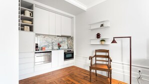 A kitchen with white cabinets, a marble backsplash, and a wooden floor. - GuestReady - Porto Charming Retreat (Porto)