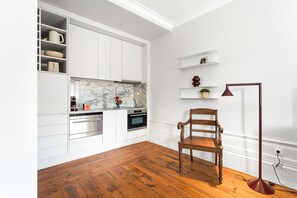 A kitchen with white cabinets, a marble backsplash, and a wooden floor. - GuestReady - Porto Charming Retreat (Porto)