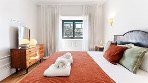 A hotel room with a bed, a dresser, a window with curtains, and a view of the outdoors. - GuestReady - Porto Charming Retreat (Porto)