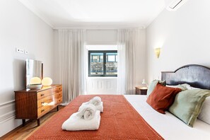 A hotel room with a bed, a dresser, a window with curtains, and a view of the outdoors. - GuestReady - Porto Charming Retreat (Porto)