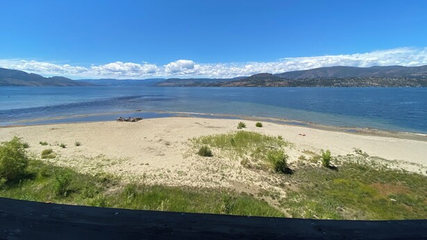 A beach with clear water, distant mountains, and a clear sky. - Lakefront Luxury Retreat - Beach & Mountain Views  (Kelowna)