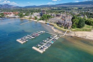 Eine Vogelperspektive auf eine Marina mit vertäuten Booten, eine Mole, die ins Wasser ragt, und ein Wohngebiet mit Gebäuden im Hintergrund.