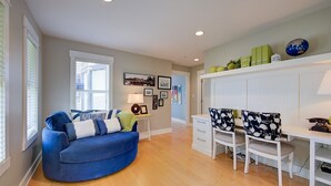 A living room with a blue sofa, a white table, and a white cabinet with shelves. - Lakefront Luxury Retreat - Beach & Mountain Views  (Kelowna)
