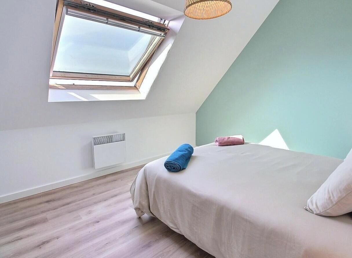 A bedroom with a skylight, a bed with pillows, and a radiator.