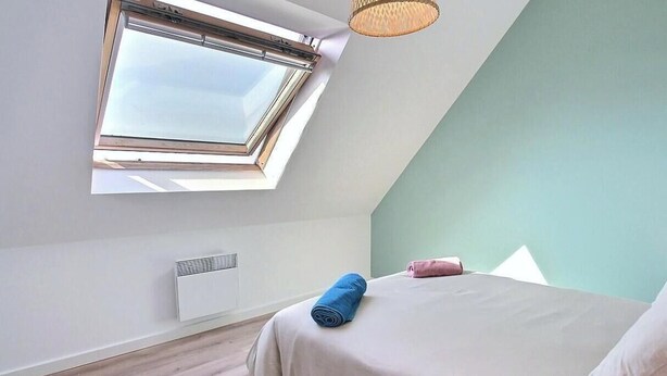 A bedroom with a skylight, a bed with pillows, and a radiator. - Ty Maezou - LANNION - Vacation Rental (LANNION)