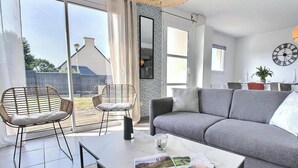 A living room with a grey sofa, two wicker chairs, a coffee table, and a dining table set for two. - Ty Maezou - LANNION - Vacation Rental (LANNION)