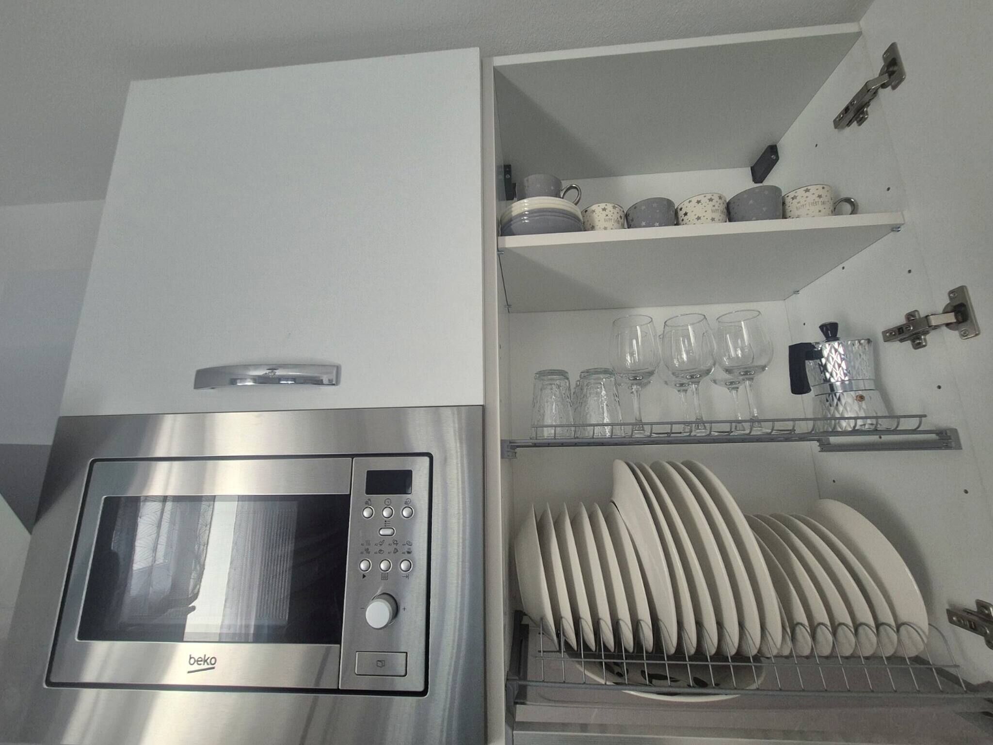 A kitchen with a built-in microwave oven and a dish rack.