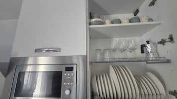 A kitchen with a built-in microwave oven and a dish rack.