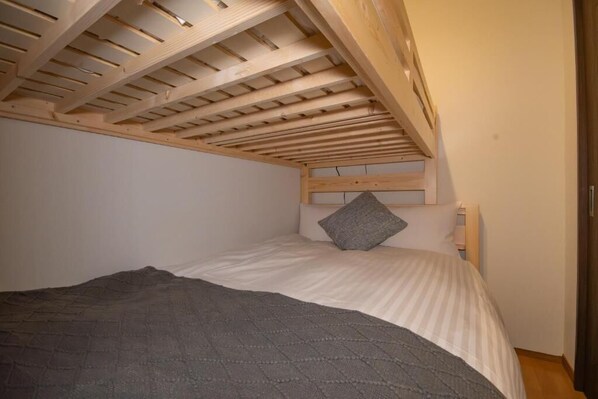 A single bed with a headboard, a grey blanket, and a wooden ceiling structure. - Rojuman Hakata (Fukuoka City Hakataku Katakasu)