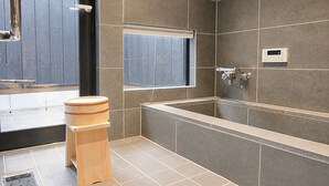 Un bagno moderno con una vasca da bagno ampia, uno sgabello di legno e una finestra.