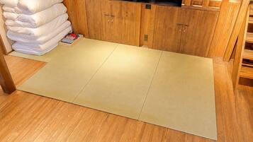 A room with a tatami mat floor, wooden cabinets, and a stack of white pillows.