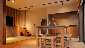 Un interno moderno con una scala in legno, una zona pranzo con tavolo e panche, e un angolo cottura con lavello ed elettrodomestici.