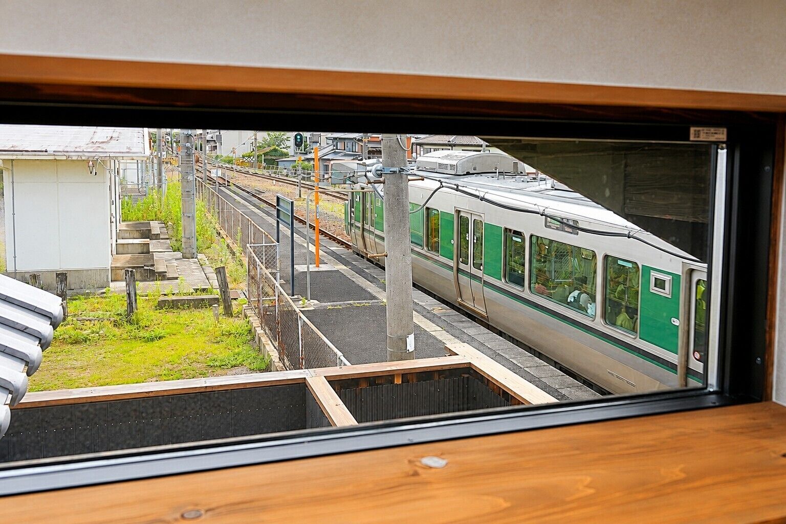 A train station platform with a train on the tracks and a building in the background.