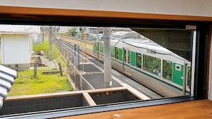 Una banchina di stazione ferroviaria con un treno sui binari e un edificio sullo sfondo.