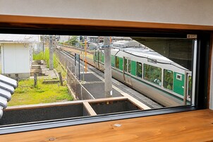 Un andén de estación de tren con un tren sobre las vías y un edificio al fondo.