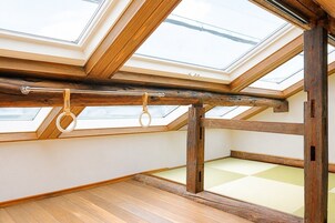 Una habitación con techo inclinado, tragaluces y estructura de vigas de madera.