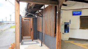 Una struttura in legno con una porta, una macchina per distributore e un cartello blu al muro.