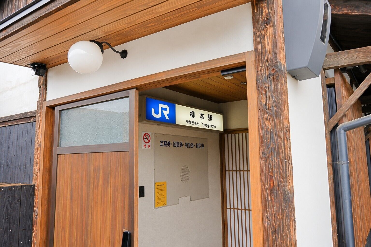 Une entrée en bois avec une enseigne indiquant le nom d’une entreprise en japonais.