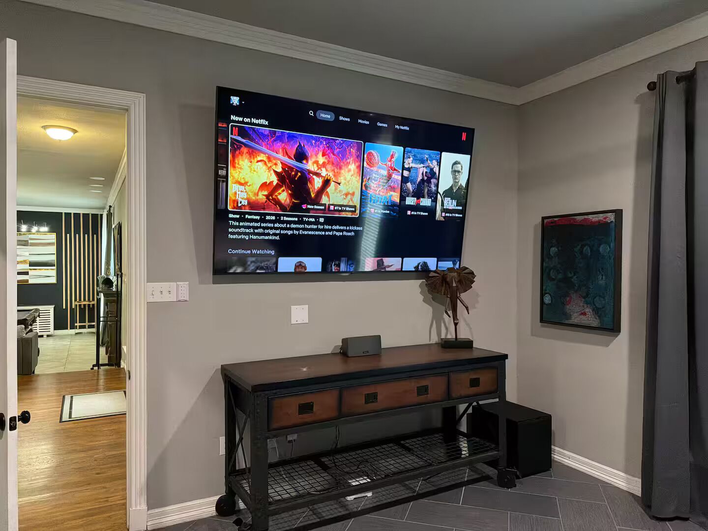 Een woonkamer met een flatscreen-televisie aan de muur, waarop een Netflix-interface te zien is.