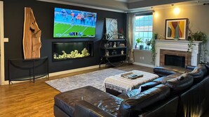 Ein Wohnzimmer mit Ledersofa, Flachbildfernseher, Kamin und Deckenventilator.