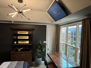 Ein modernes Schlafzimmer mit einem Bett, einem Schreibtisch, einem Fernseher und einer Pflanze.