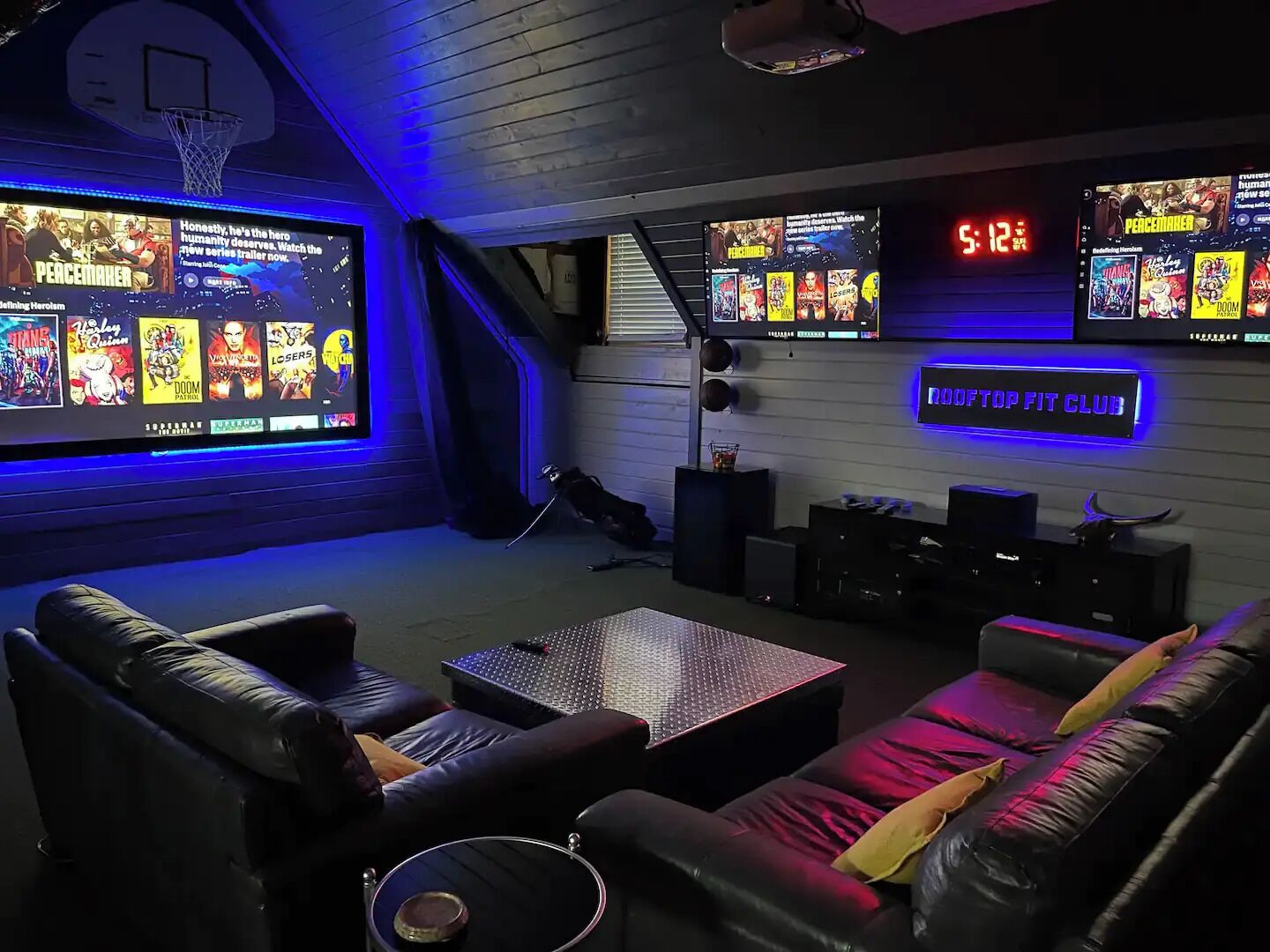 A home theater room with a large screen, multiple speakers, and a clock.